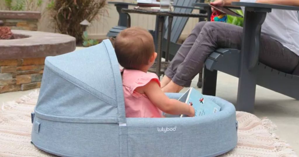 a baby sitting outside in a Lulyboo travel lounge and nest