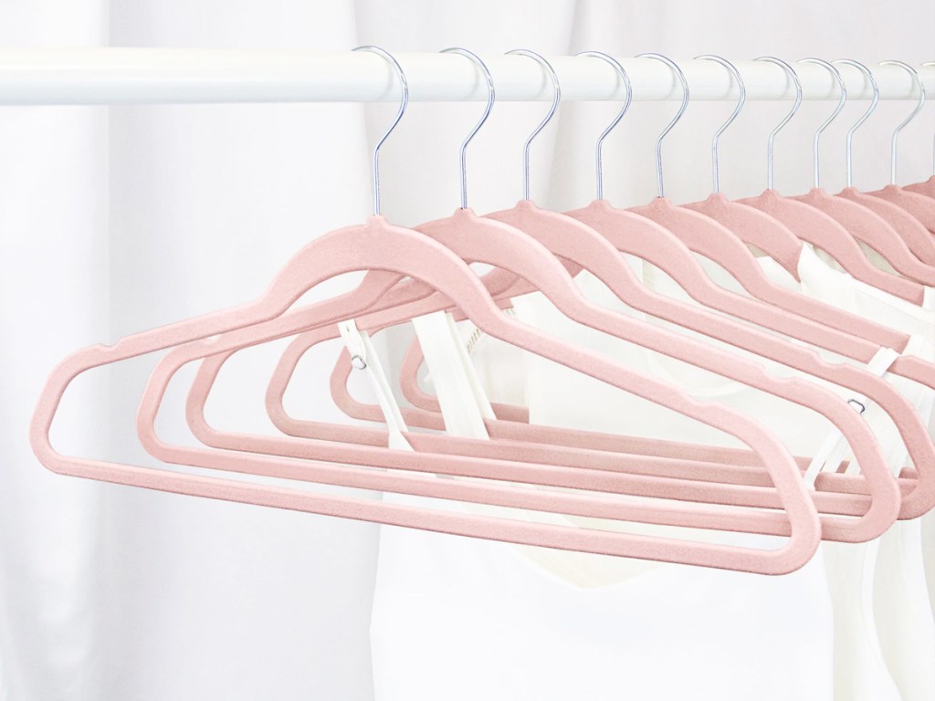white tank tops hanging on pink velvet hangers in closet