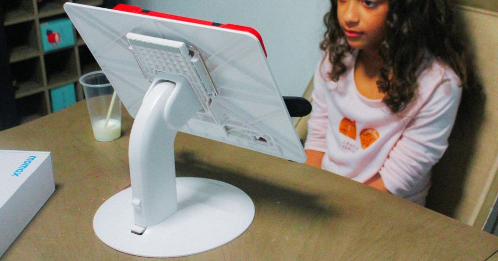 kid sitting in front of white laptop stand with ipad 