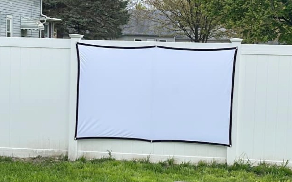 A movie projector screen that a reader hung from a fence using command strips