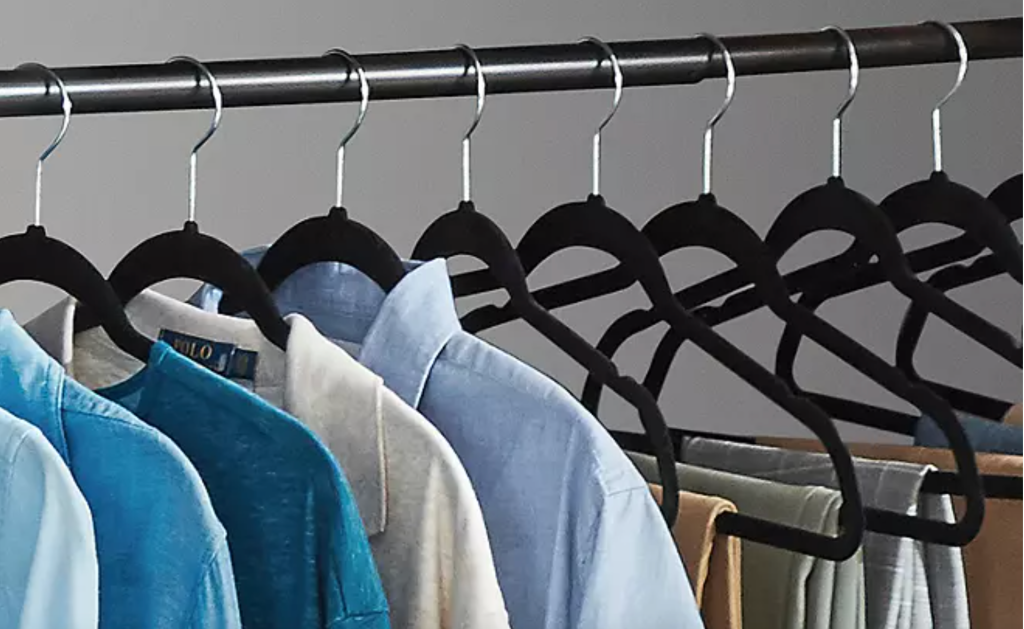 shirts and pants hanging on black velvet hangers in closet