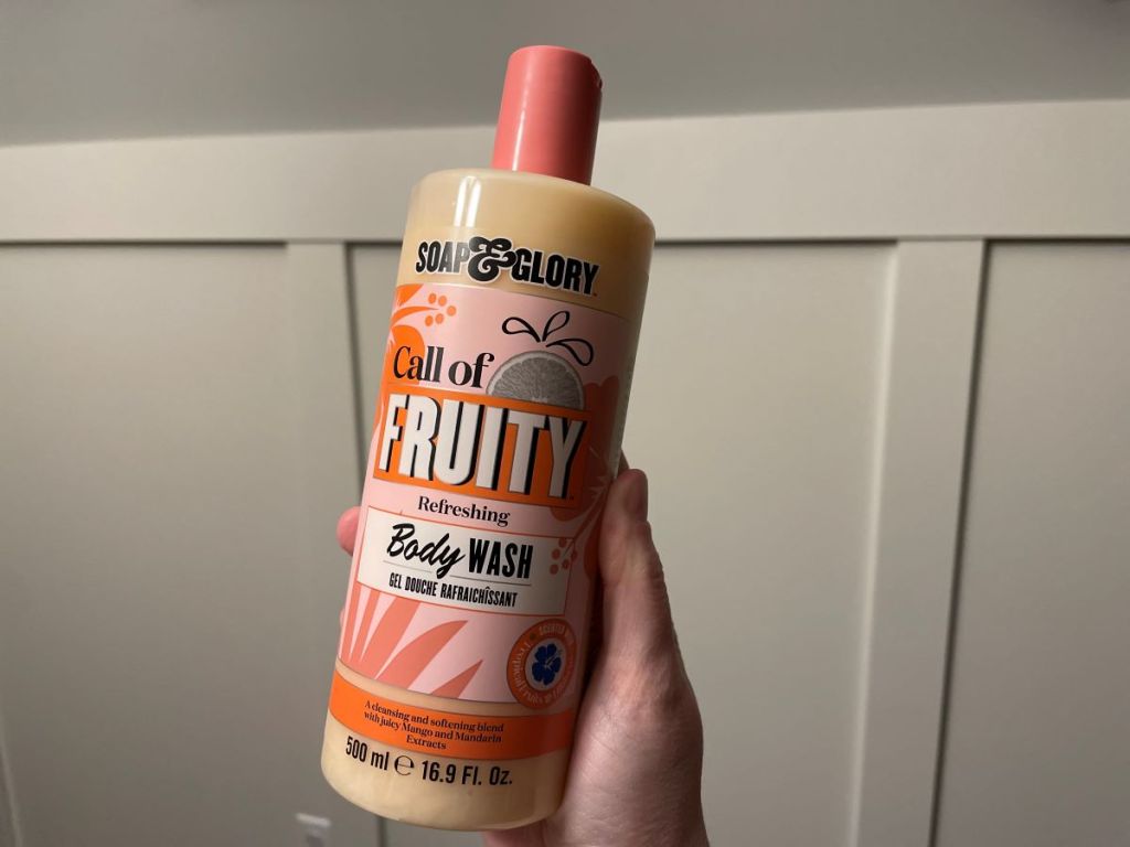 Hand holding a big bottle of Soap & Glory body wash