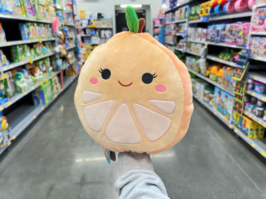 Hand holding a Squishmallow that looks like an orange