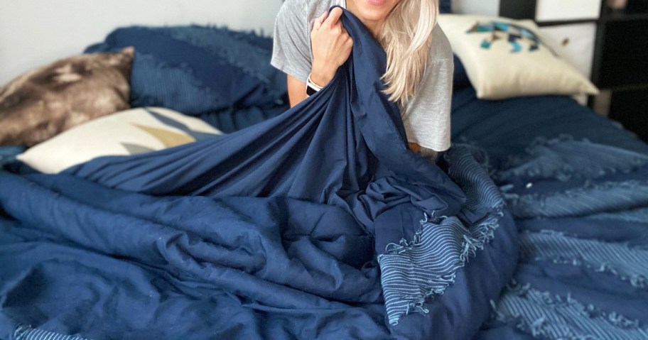 woman sitting on a bed made with dark blue sheets