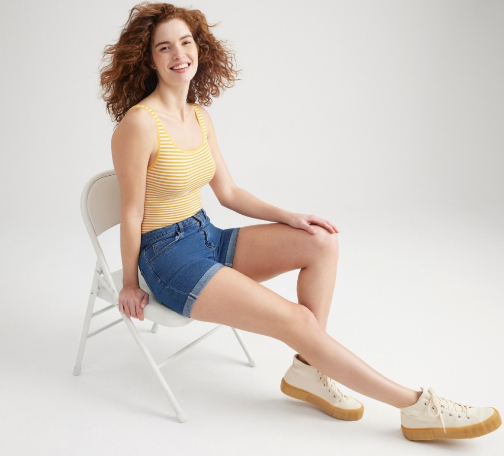 Woman in a yellow and white striped bodysuit and denim shorts
