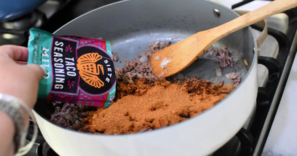 adding siete taco seasoning to a skillet