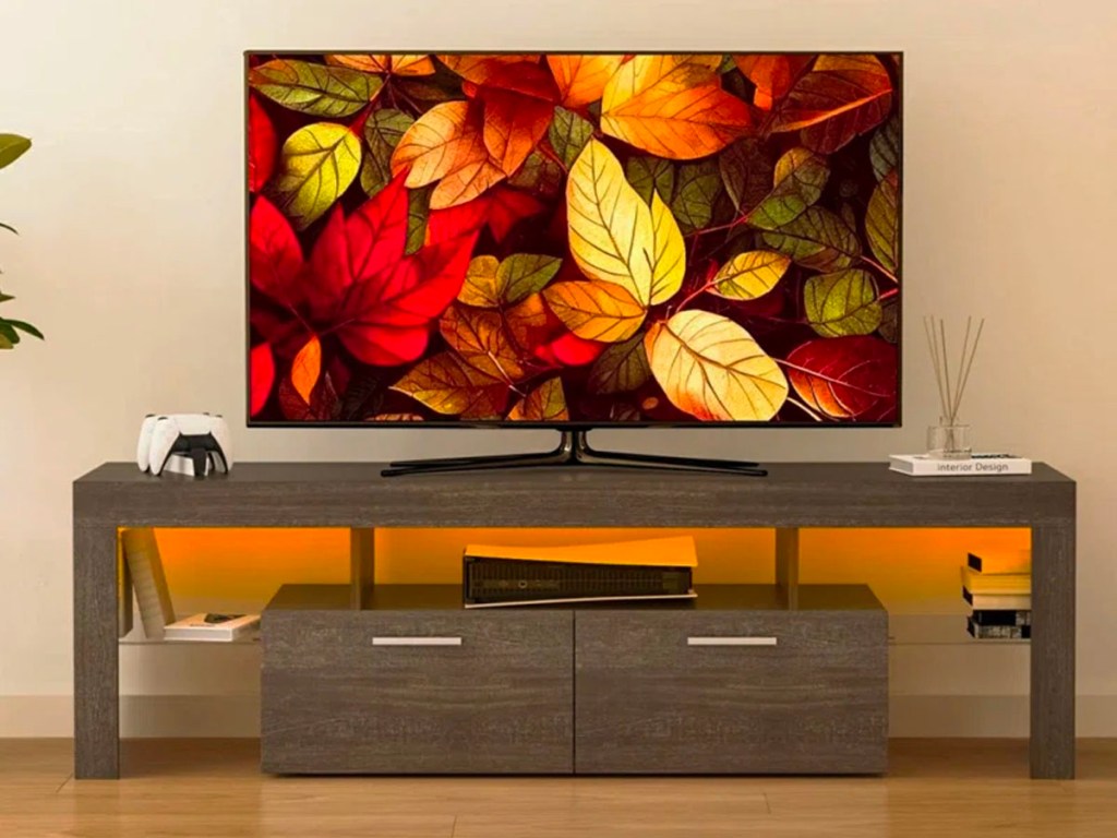tv with leaves displayed sitting on gray tv stand and LED lights