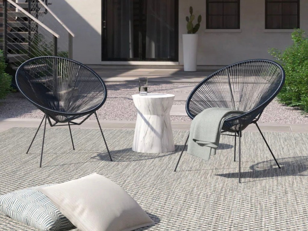 two black rope patio chairs on patio with gray blanket hanging off