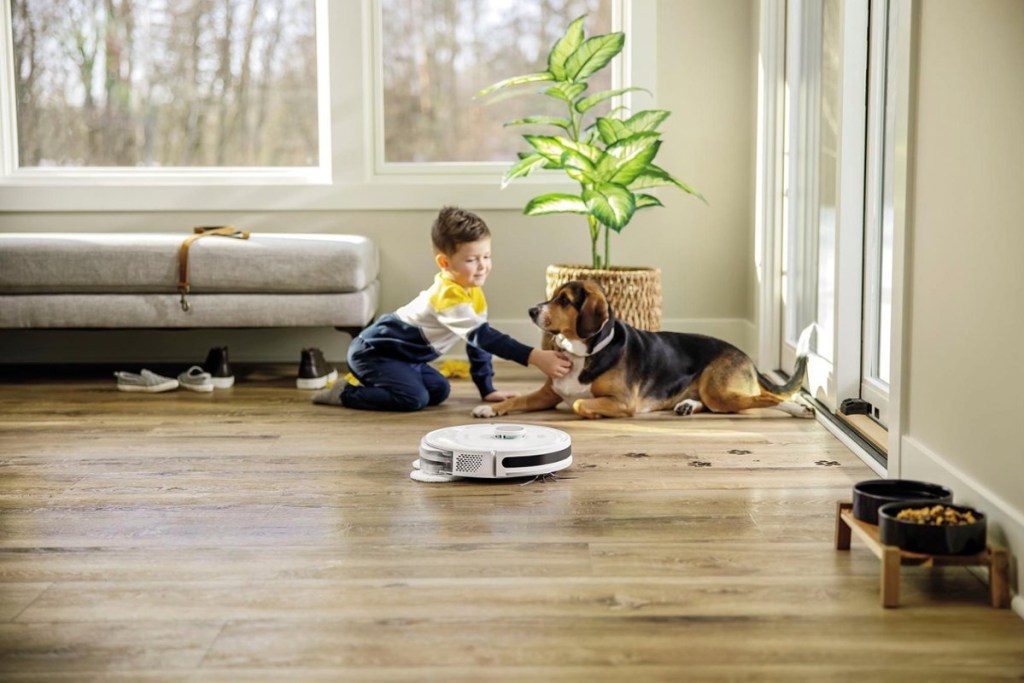 robot vacuum running in room with boy and dog