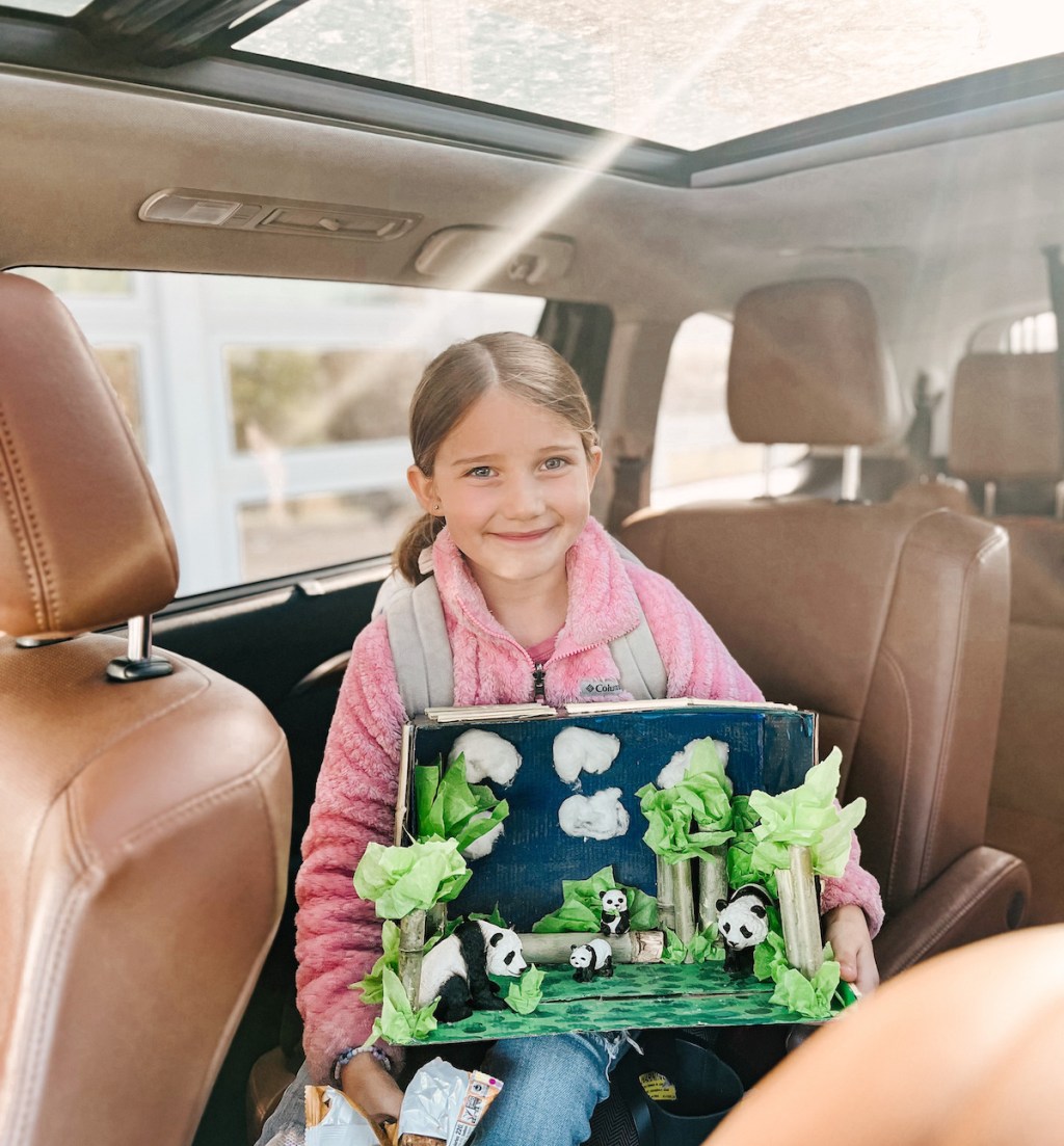 girl holding panda shoe box project sitting in car