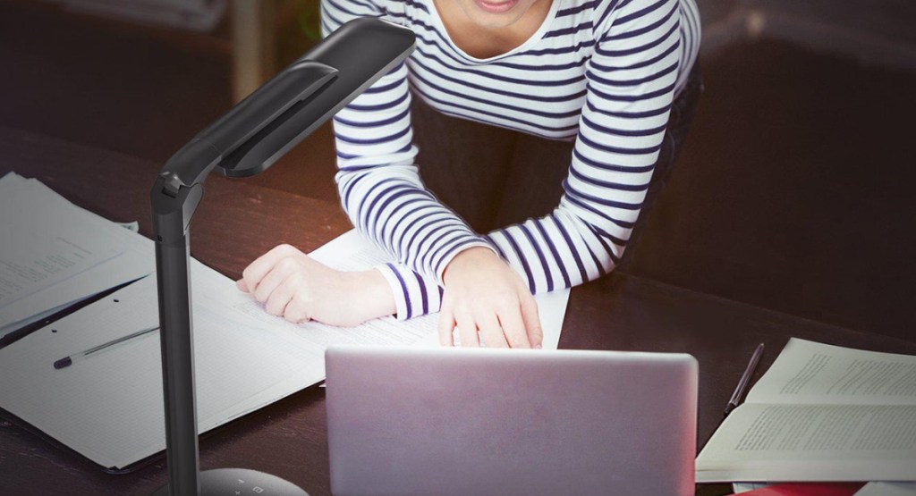 lamp shining on woman as she types on her laptop