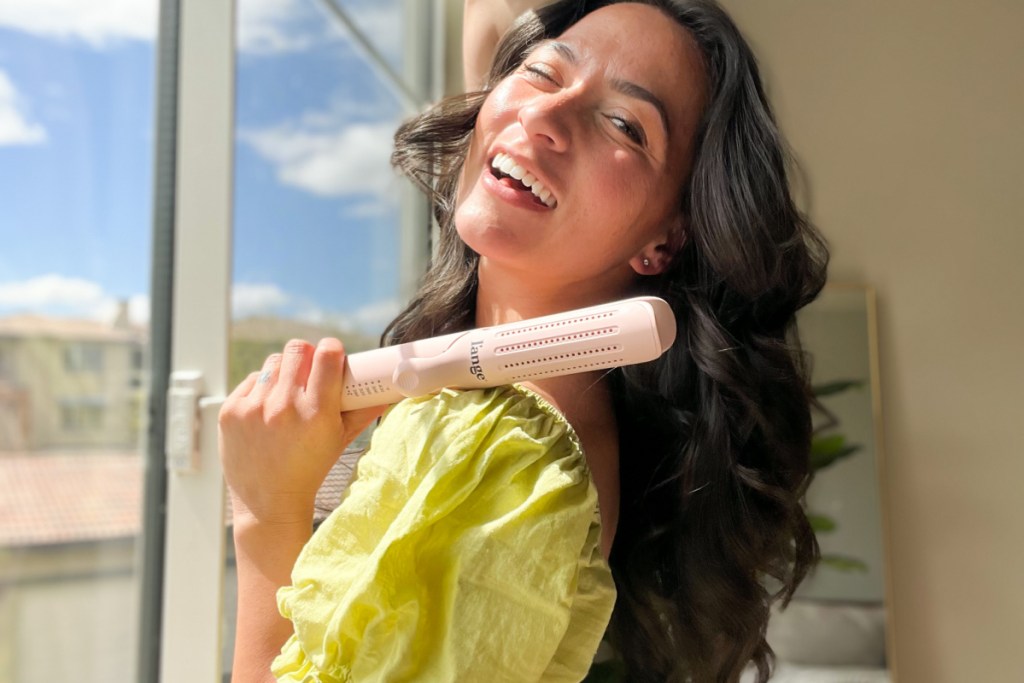 woman holding curling iron over shoulder