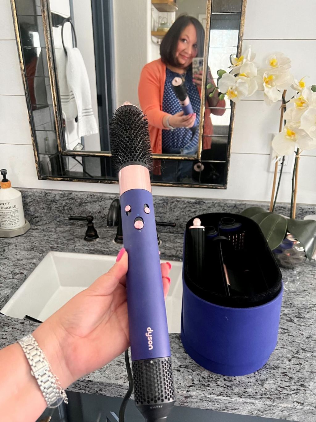 woman holding dyson hairwrap in mirror