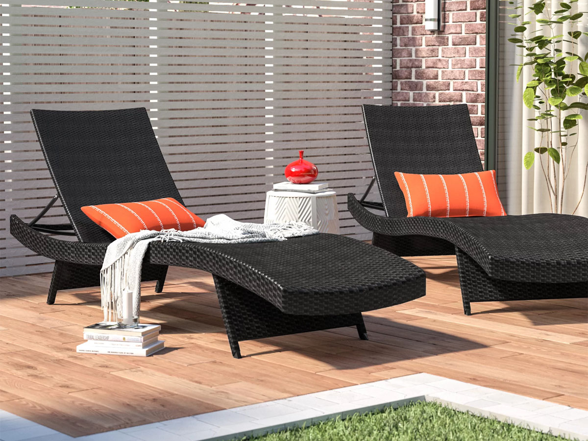 two black chaise reclined chairs with orange pillows 