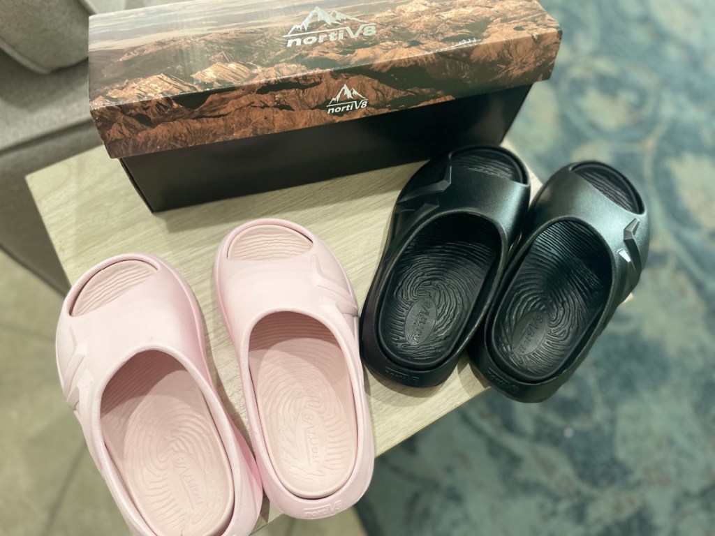 black and pink slide sandals next to shoe box