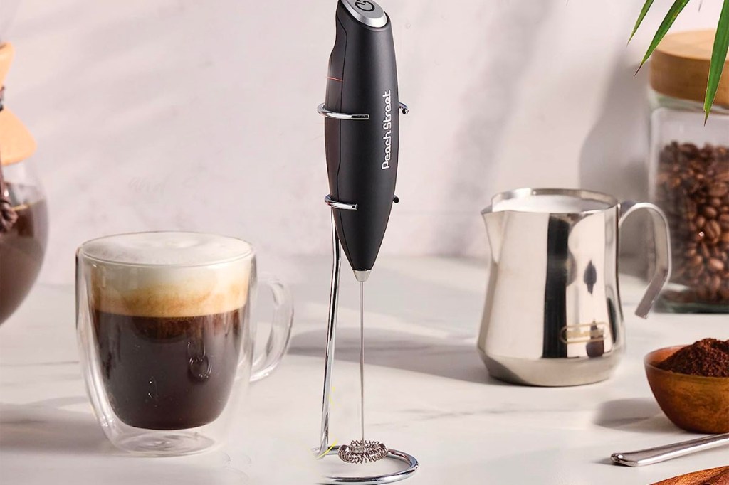 peach street milk frother sitting on table next to coffee cups
