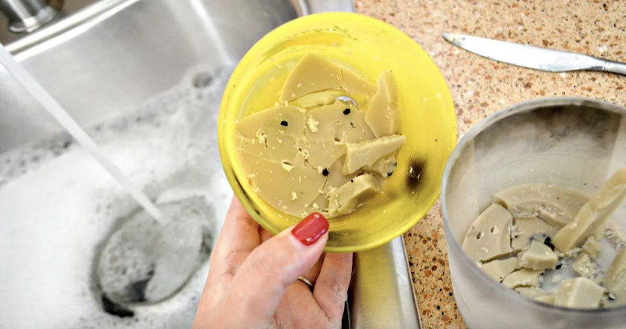 hand holding old candle with wax over sink