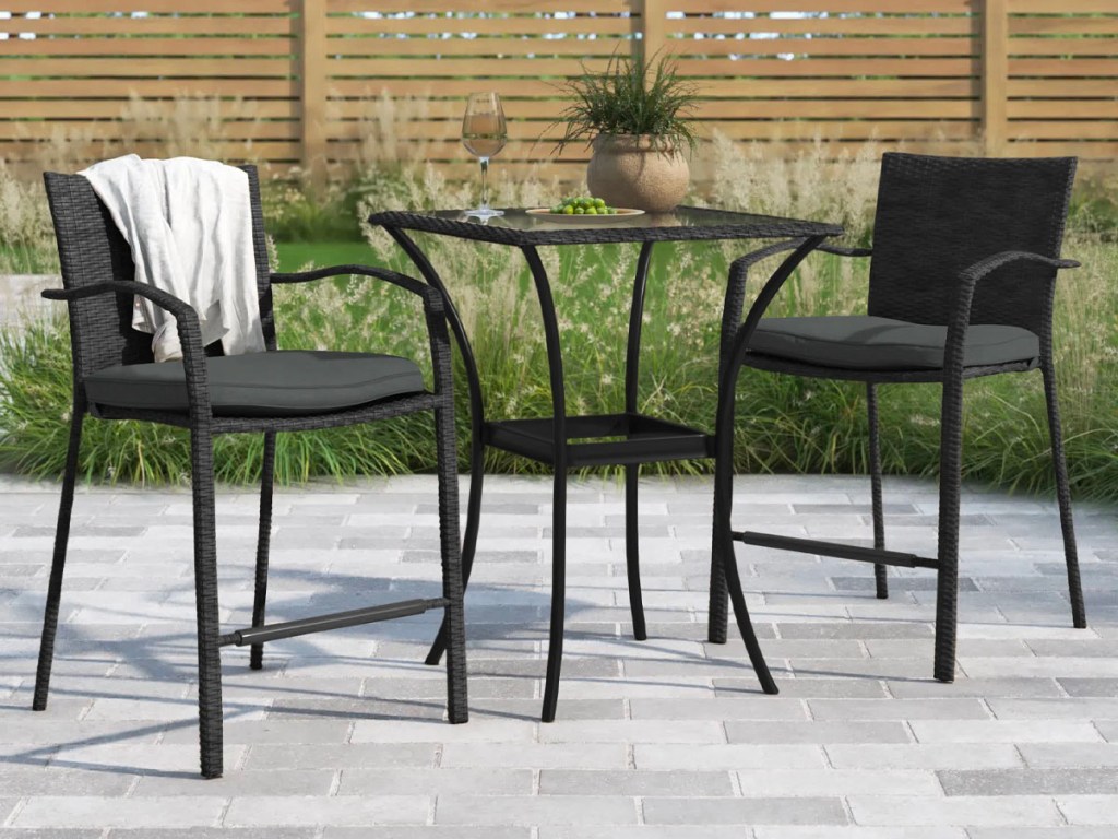 black bistro set with two tall chairs and black table on patio