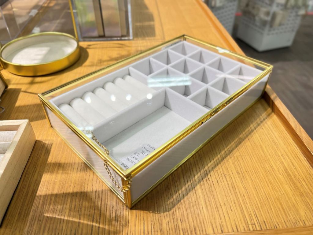 White jewelry organizer with gold trim and a glass lid