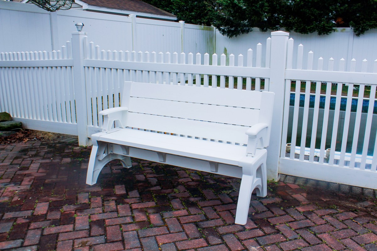 a convert-a-bench from qvc propped up near a white fence