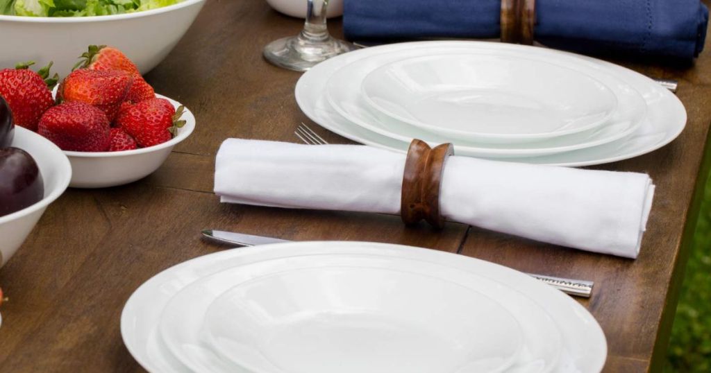 A table set with white plates and silverware wrapped in white napkins