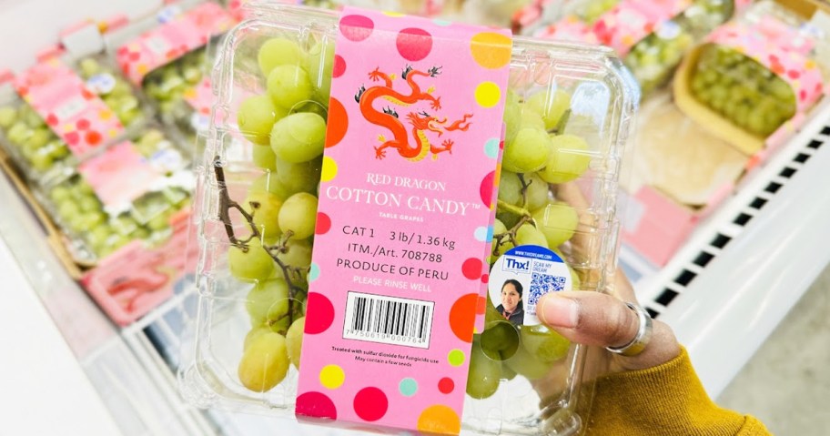 hand holding up a large container of Cotton Candy Grapes