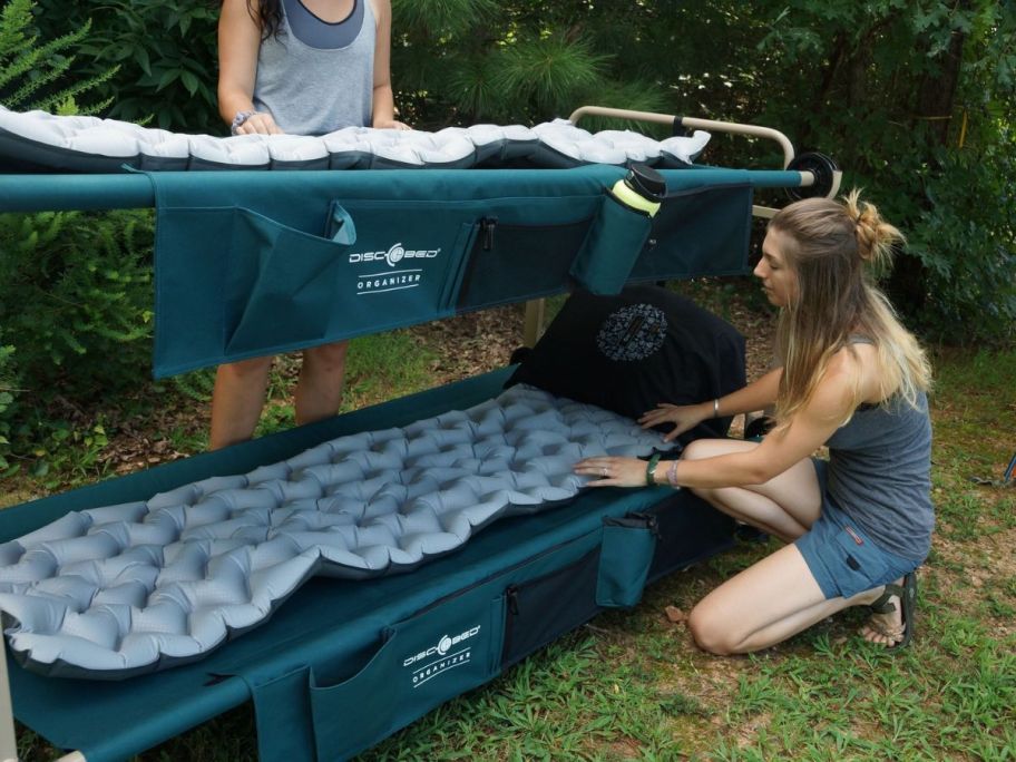 two girls setting up a Disc-O-Bed outdoors on grass