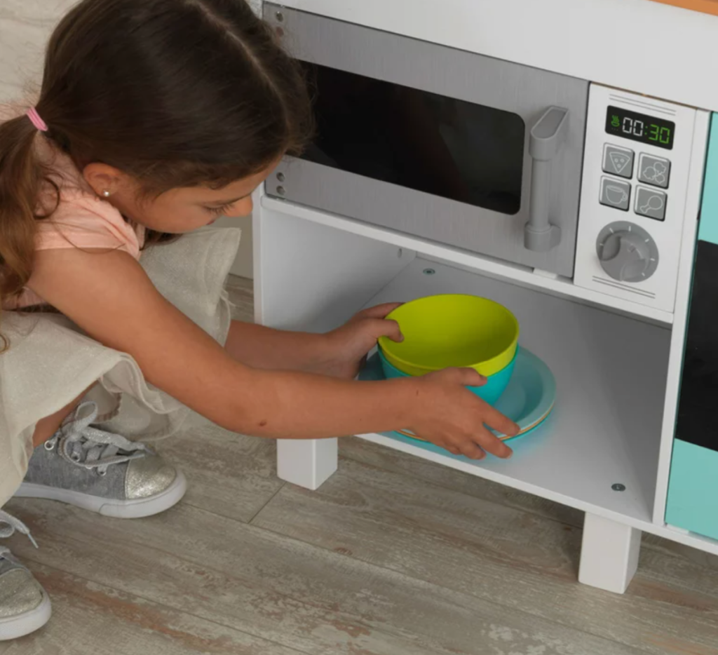 Young girl playing with her KidKraft Gourmet Kitchen Playset from Walmart