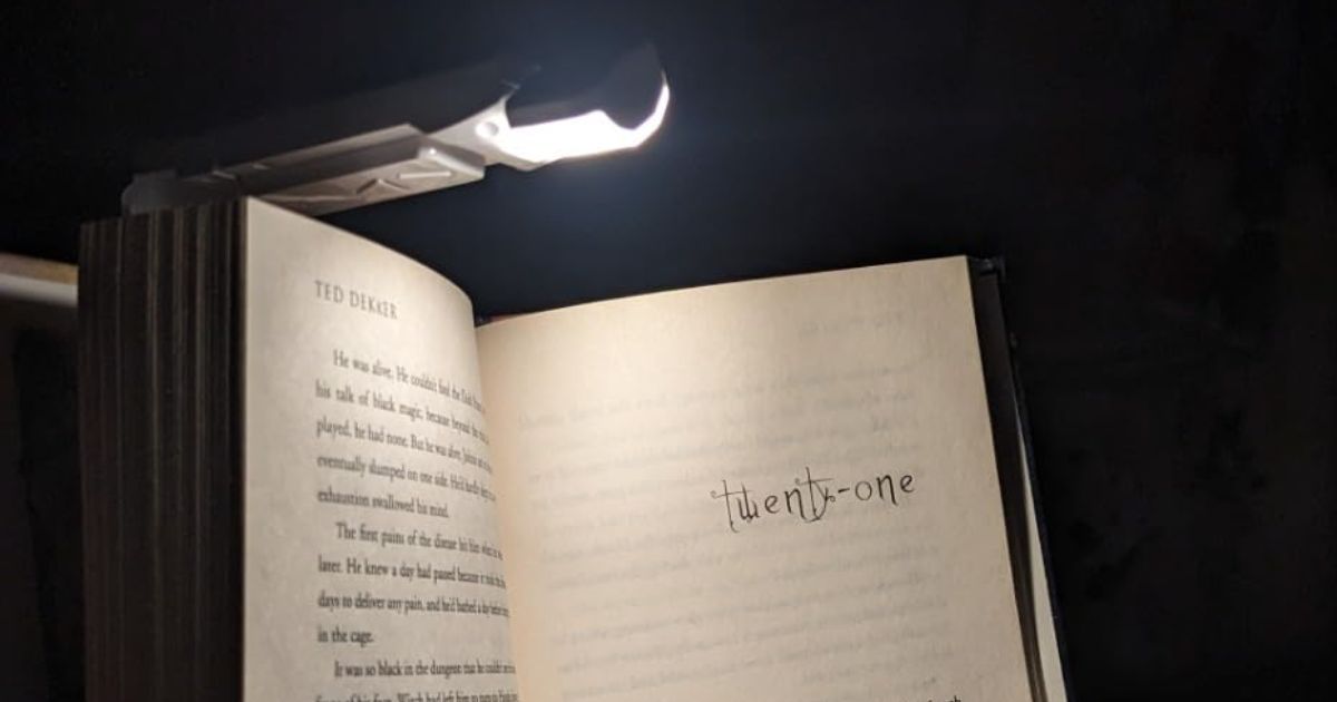 book light shining onto a book a person is reading