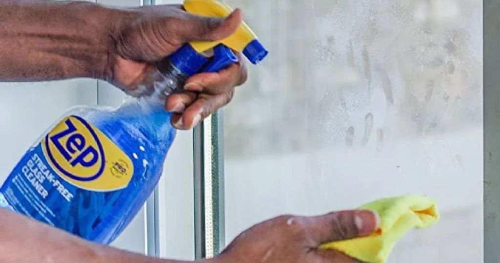 man using Zep Streak-Free Glass 32oz Cleaner on a window