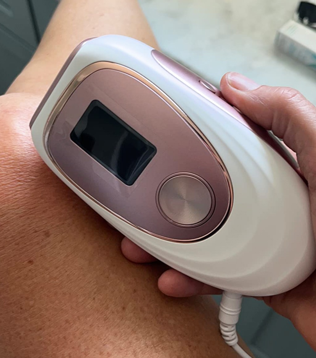 hand holding IPL device next to leg