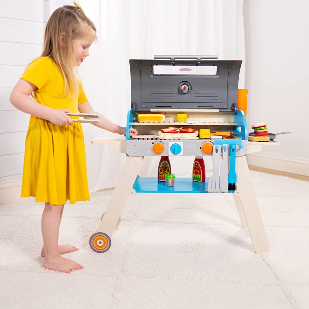 Girl standing next to a wooden grill playset