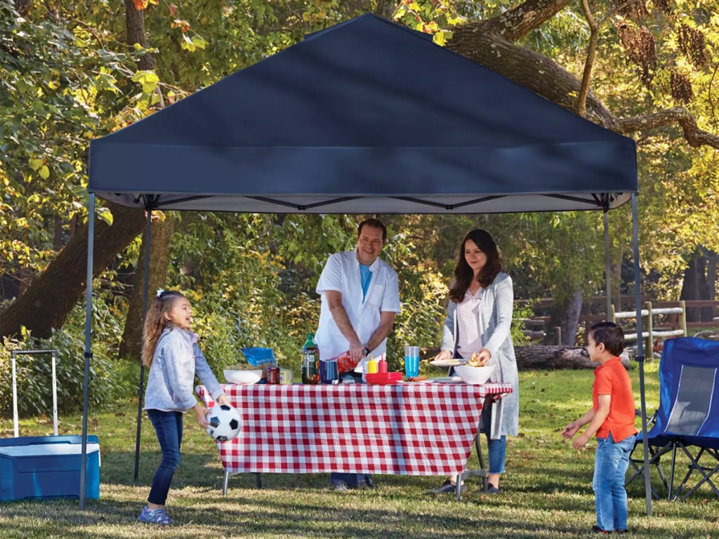 family under a blue pop-up canopy