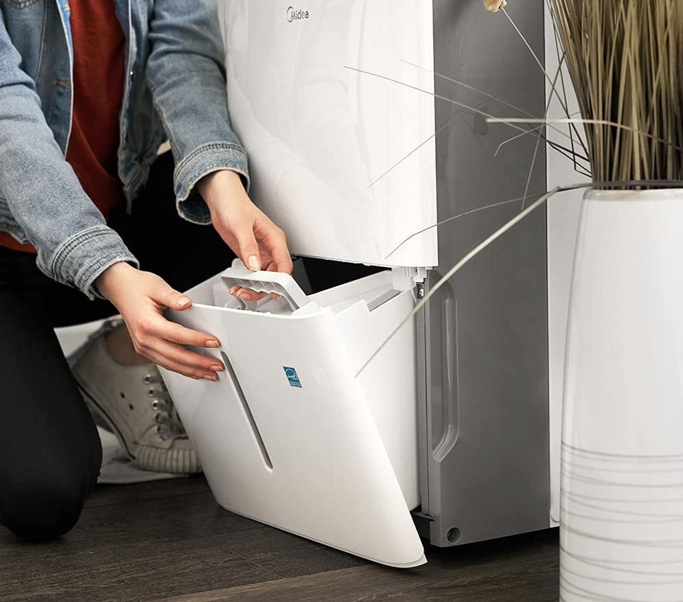 Woman opening a dehumidifier bucket