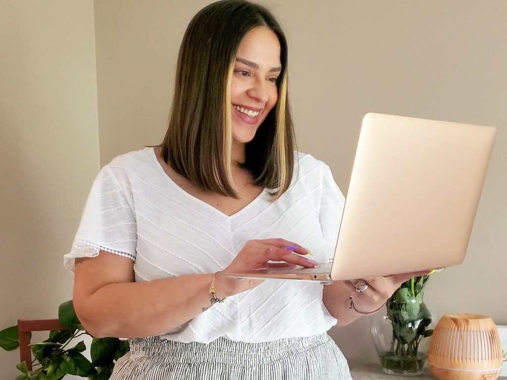 woman in white shirt holding up a laptop