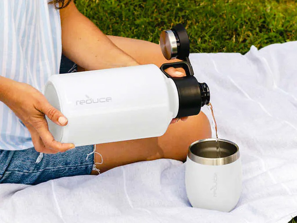 pouring drink from white growler into matching white wine tumbler