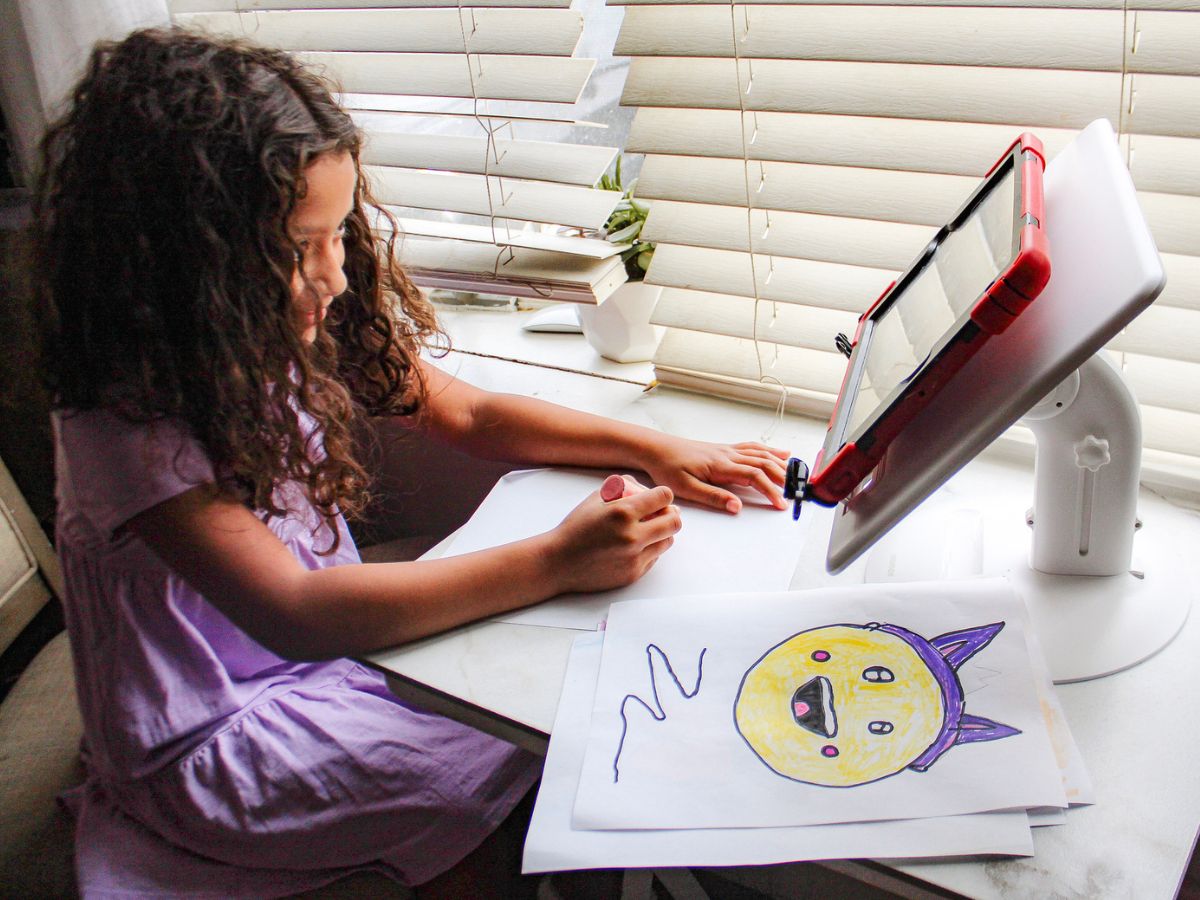 Little girl drawing while using a momax tablet stand to hold her ipad 