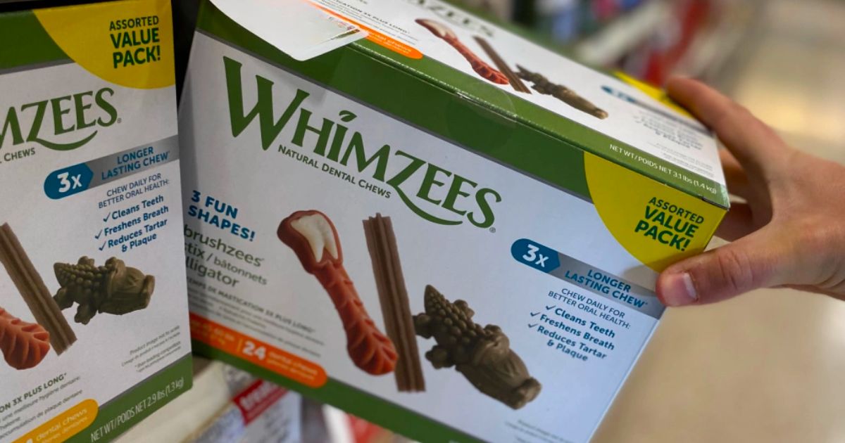 a mans hands grabbing a box of Whimzees dog treats variety pack from a store shelf