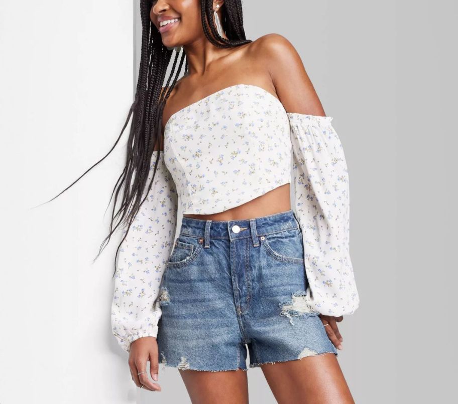 a woman wearing a pair of distressed denim cutoff high rise jean shorts