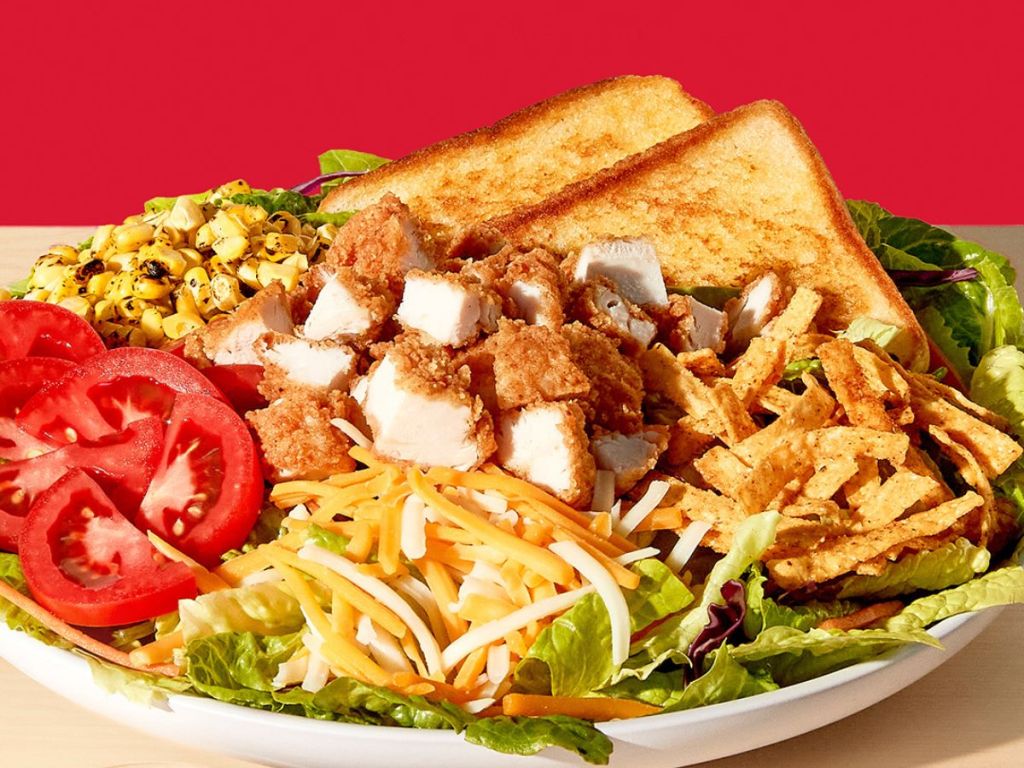 Zaxby's southwest salad in a bowl with tomatoes, chicken, cheese, and greens