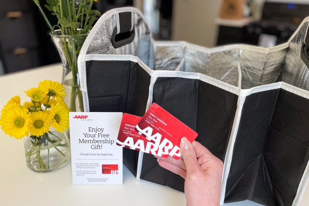 woman holding aarp membership cards in front of a trunk organizer