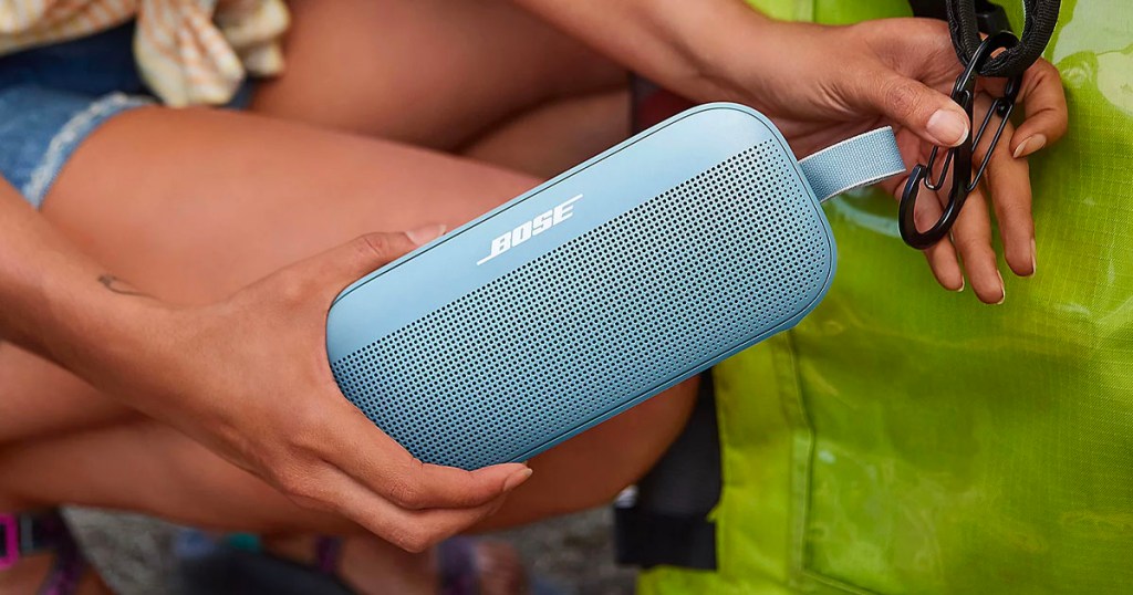 hand holding baby blue bose bluetooth speaker being clipped on bag