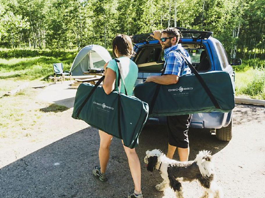 couple holding their discobed inside of their bags as they find a place to camp