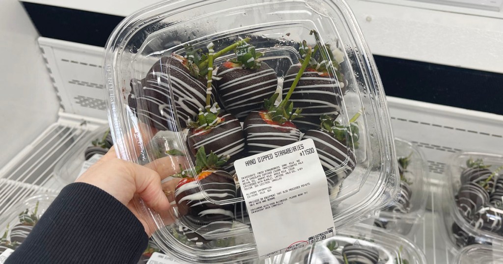 hand holding container full of hand dipped strawberries