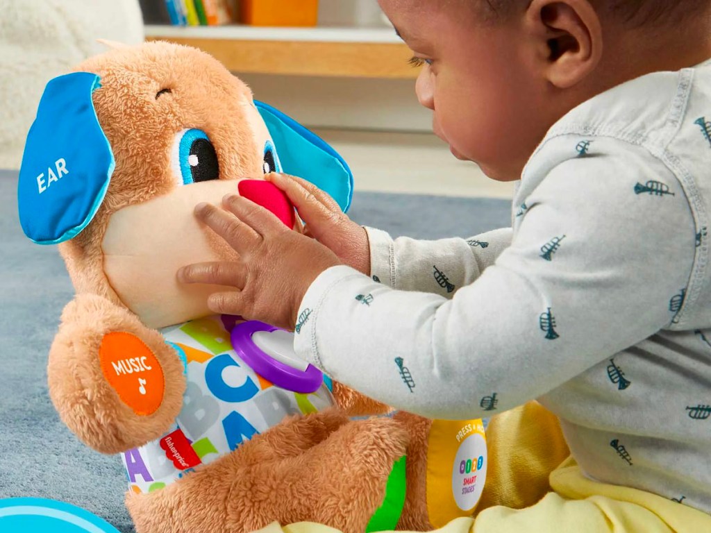 baby playing with blue fisher price puppy toy