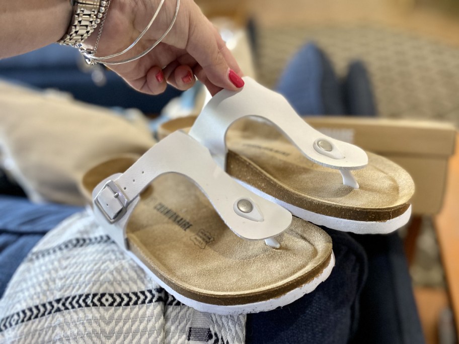 hand holding Cushionaire Leah Cork Footbed Sandals in white