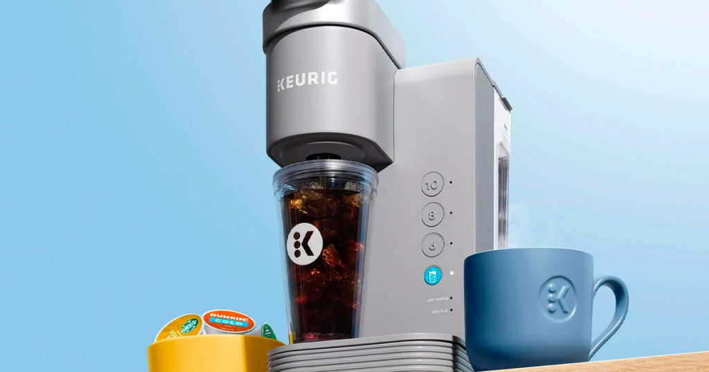 gray keurig iced coffee make brewing in tumbler with blue coffee mug next to it