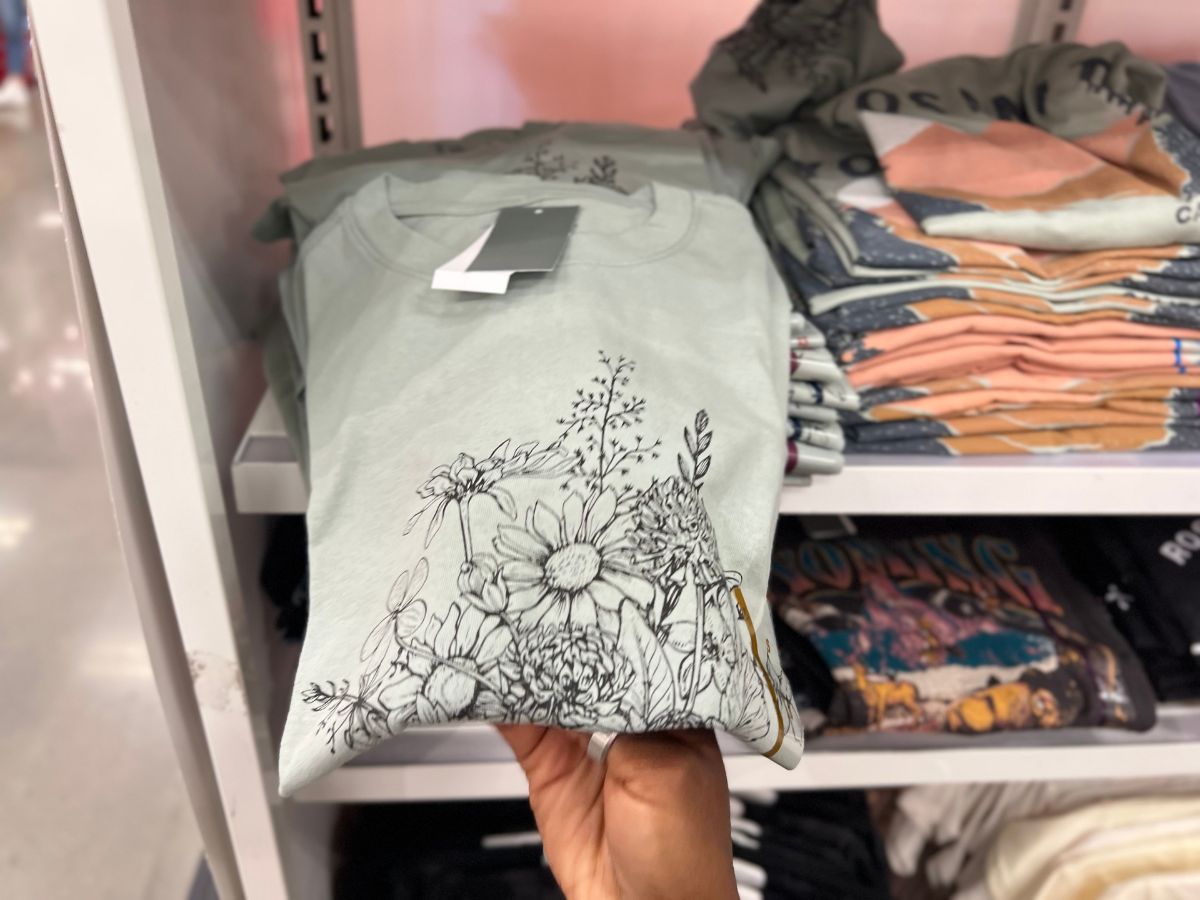 hand holding green floral tee in store