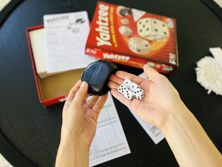 hands holding dice with yahtzee board game in background