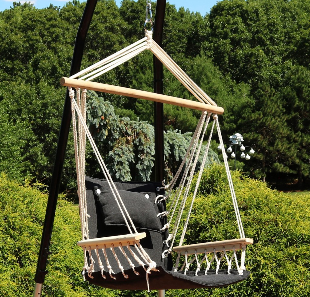 hanging chair with pillow on metal stand in outdoor space